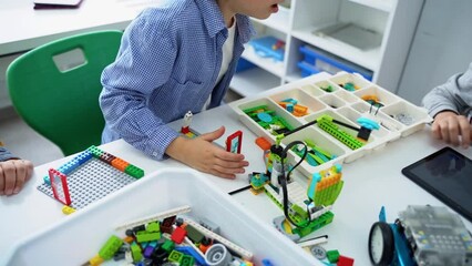 Robotics programming class. Children construct and code Robot. STEM education using constructor blocks and laptop tablet, remote control joystick. Technology educational development for school kids - Powered by Adobe