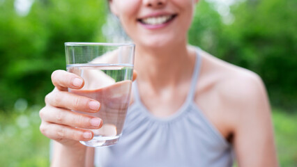 Woman holding a glass of water on green nature background