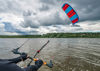 Hands of kitesurfer hold kitesurfing bar with run kite in air