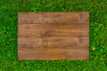 Empty wooden desk board on green grass as design template