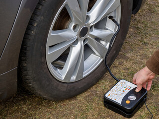 Pump for pumping up a car wheel. Tire inflation on the road. The use of a wheel repair kit.