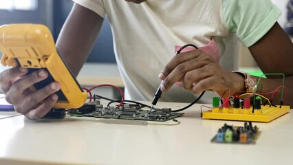 African student girl fixing circuit board with electrical tester in the engineering technology course