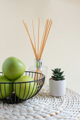 Modern set on a beige background fruit bowl with apples and a straw stand. Copy space, interior accessories.