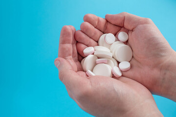 Pills and medicines in hand against a blue background.