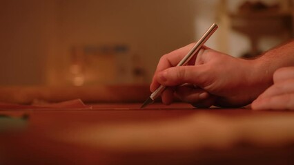 Male hand of craftsman with furrier knife scalpel cuts leather material 