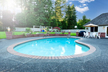 Heart shaped home swimming pool in large backyard during summer daylight
