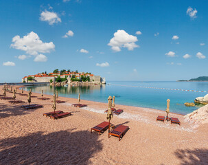 Pink sandy Milocher Beach and Sveti Stefan islet morning view (Montenegro, near Budva). People unrecognizable.