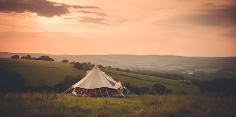 Fototapeta na wymiar Witness the breathtaking beauty of nature with a tent set up in a field, against the backdrop of a stunning sunset. This natural landscape is the perfect natural wallpaper