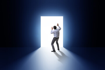 Businessman entering backlit door in escape concept