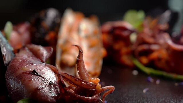 Grilled octopus with calmars, salad and lemon on plate. Close up view.