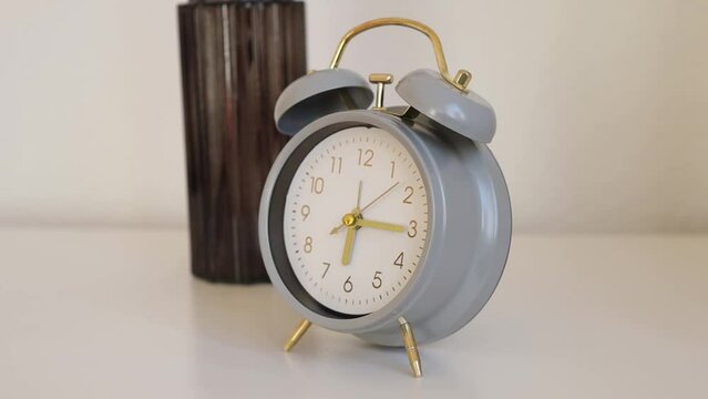 Gray alarm clock stands on a white table in the room