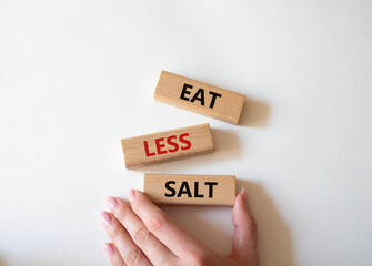 Eat less salt symbol. Concept word Eat less salt on wooden blocks. Businessman hand. Beautiful...