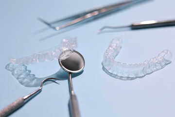 Transparent plastic aligners and dentist's tools on a colored background