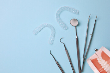 Transparent plastic aligners and dentist's tools on a colored background