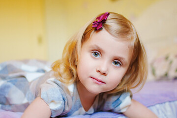 a portrait of a cute little girl in a plaid dress in the bed. 