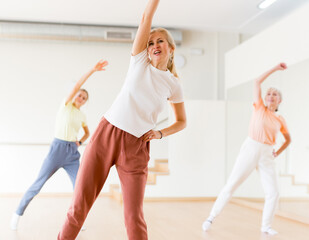 Woman doing bending sideways on group fitness training in studio.