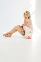 Naklejka premium a gentle naked blonde woman in a white shirt on the floor. 