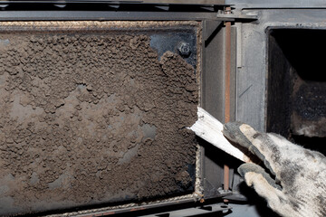 A man cleans a solid fuel boiler from soot and soot. Maintenance of heating equipment after the heating season