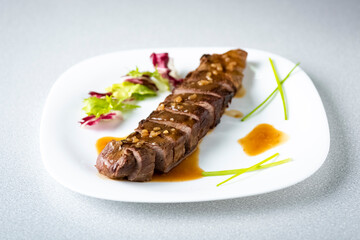 a sliced steak poured with onion decorated with lettuce leaves