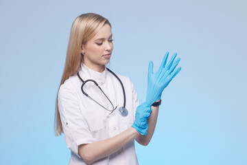 girl doctor puts on washable blue gloves on a clean blue background