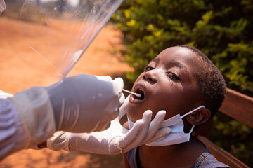 A doctor performs a coronavirus test on a child in Africa and inserts the swab down his throat