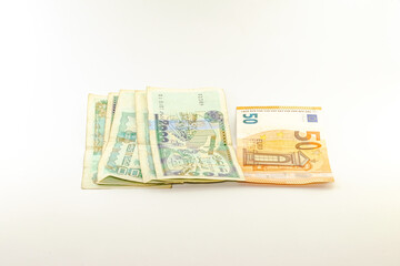 Fifty Euros bill and five bills of two thousand Algerian dinars which is equivalent to ten thousand dinars on black background.