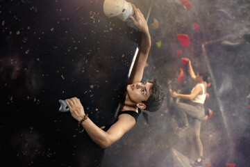 Sporty strong young man exercising in boulder climbing hall without rope, reaching new results,...