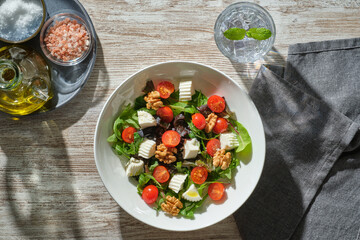 shot from above of a white plate full of healthy fresh salad illuminated with strong light