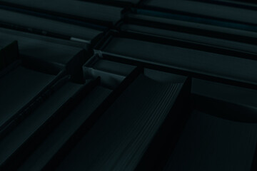 Obraz premium Deep dark background of books with black counterfoils and shady blue pages.