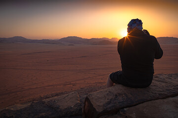 Wadi Rum w Jordanii. Mężczyzna fotografujący wschód słońca na pustyni. 