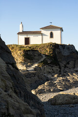 Fototapeta premium Virxe do Porto (Valdoviño) hermitage and cliffs in the Rias Altas touristic area of Galicia at sunset, Meiras, Spain.