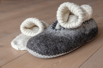 On the home wooden floor are men's slippers made of wool and knitted woolen socks