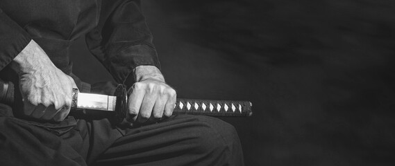 The samurai holding a Japanese katana sword, banner, in black and white. Photo of a warrior dressed...