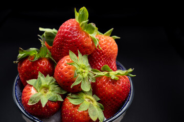 Bowl with lots of fresh strawberries on a black background.