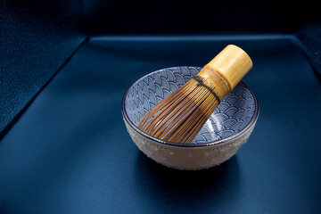 Japanese matcha tea ceremony set (traditional bowl and whisk made of bamboo) on a dark blue background.