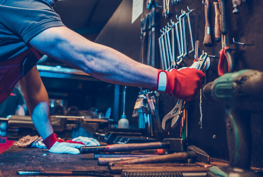 Industrial Worker Grabbing His Work Tools From Storage Wall