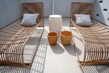 Fototapeta na wymiar Two wicker sun lounge chairs on a roof top sun deck.