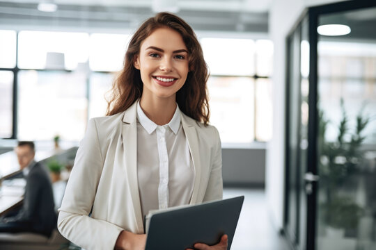 Young and ambitious insurance agent posing with a laptop in her hands and a bright smile, standing in a modern office filled with natural light, generative ai
