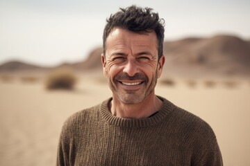 Environmental portrait photography of a pleased man in his 40s wearing a cozy sweater against a hot desert or sand background. Generative AI