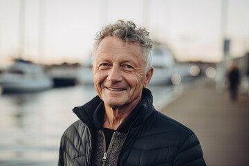 Portrait of a smiling senior man standing on the pier at sunset