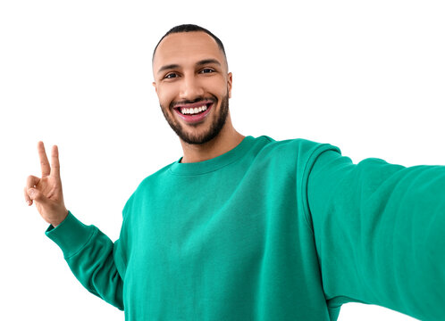 Smiling young man taking selfie and showing peace sign on white background
