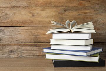 Stack of hardcover books on wooden table, space for text