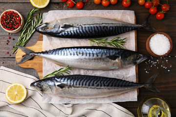 Raw mackerel, tomatoes and rosemary on wooden table, flat lay