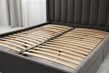 Modern bed with storage space for bedding under slatted base in room, closeup