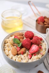 Delicious oatmeal with freeze dried strawberries, almonds and mint on table