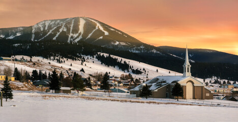 View of Discovery Ski area on Rumsey Mountain and Philipsburg community church in Philipsburg, Montana at sunset