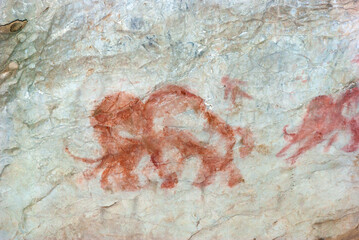 Beautiful drawings of ancient people in red ocher on the walls of a limestone cave.