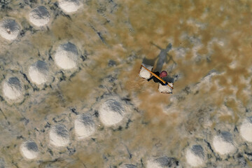  Aerial view of worker harvesting salt in salt field at Ban Laem-Thailand	