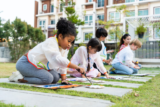 Group of student coloring on painting board outdoors in school garden. 