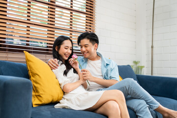 Asian young man surprise and give rose flower to beautiful girlfriend. 